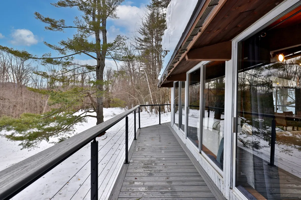 This image showcases a wooden deck surrounded by snow-covered ground and tall trees. The deck is spacious, offering ample room for seating or a BBQ setup. The surrounding wintry landscape creates an inviting atmosphere for après-ski relaxation or summer evenings outdoors.